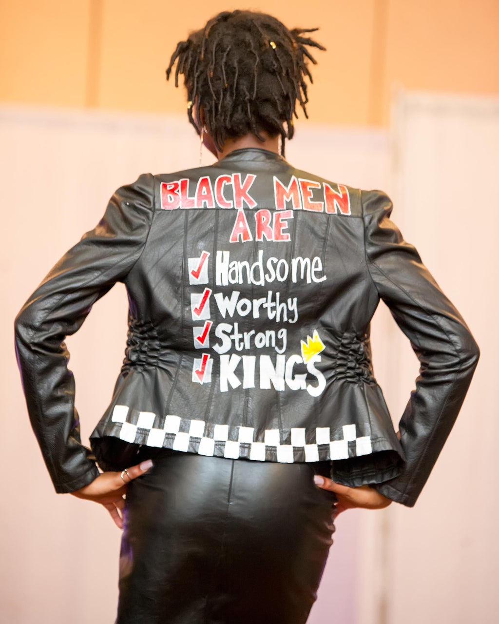 female model with black leather jacket that reads \"Black men are handsome worthy strong kings.\"