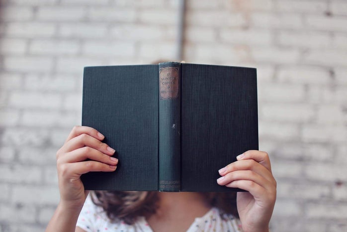 person holding an open book in front of their face