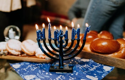lit menorah surrounded by challah and jelly donuts for hanukkah
