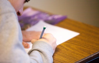 person holding pencil writing on paper