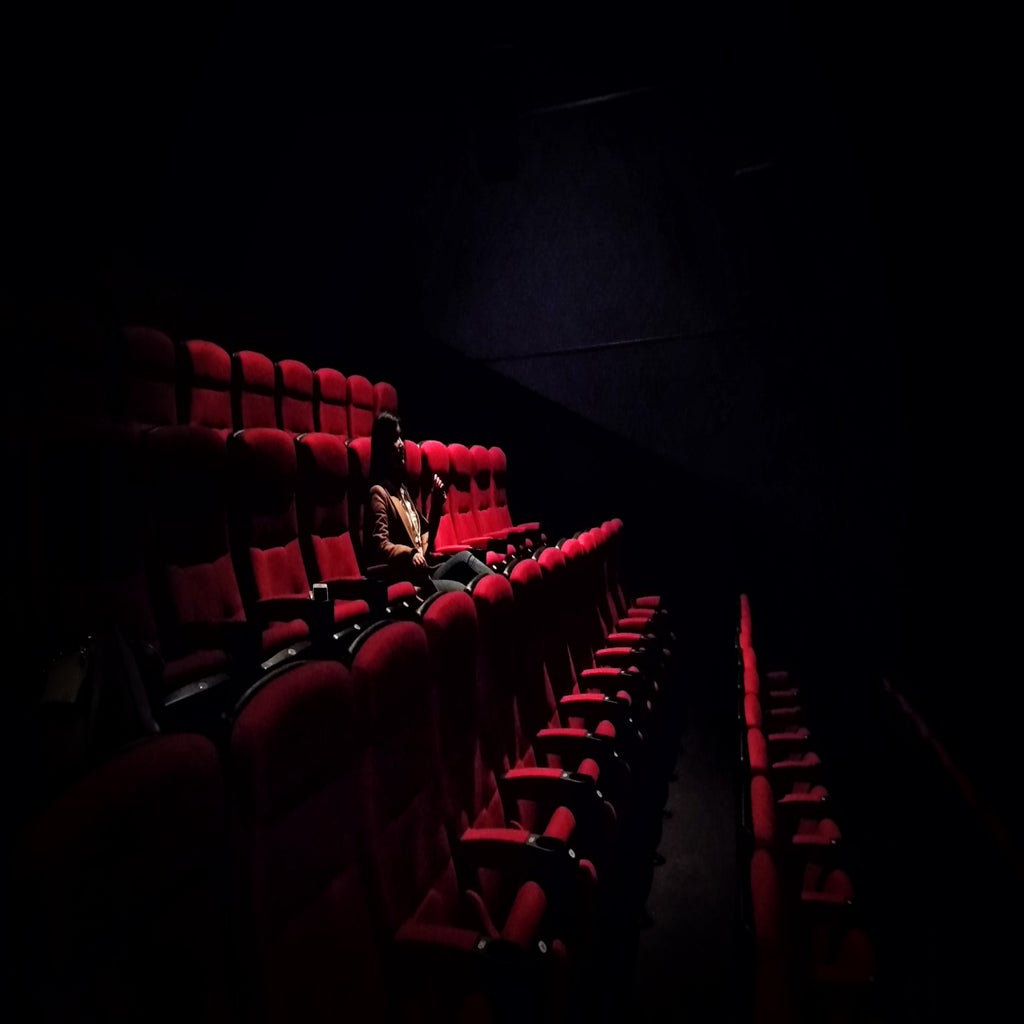 Woman sitting in dark movie theatre