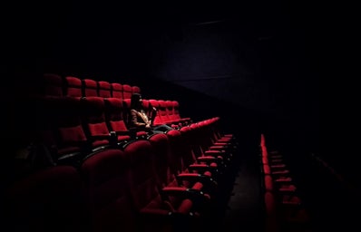 Woman sitting in dark movie theatre