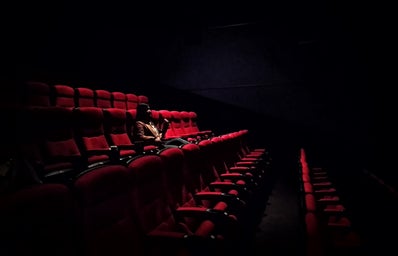 Woman sitting in dark movie theatre
