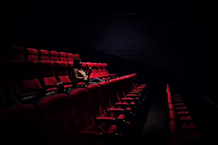 Woman sitting in dark movie theatre