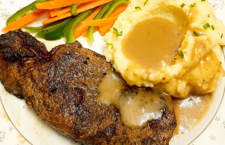 plate of mashed potatoes with gravy, vegetables, and steak