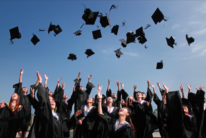 Female students throw their graduation caps in the air.