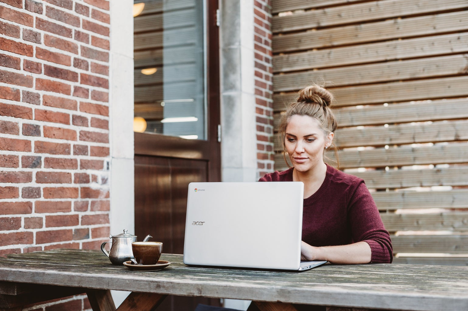 Woman working at laptop outside with coffee