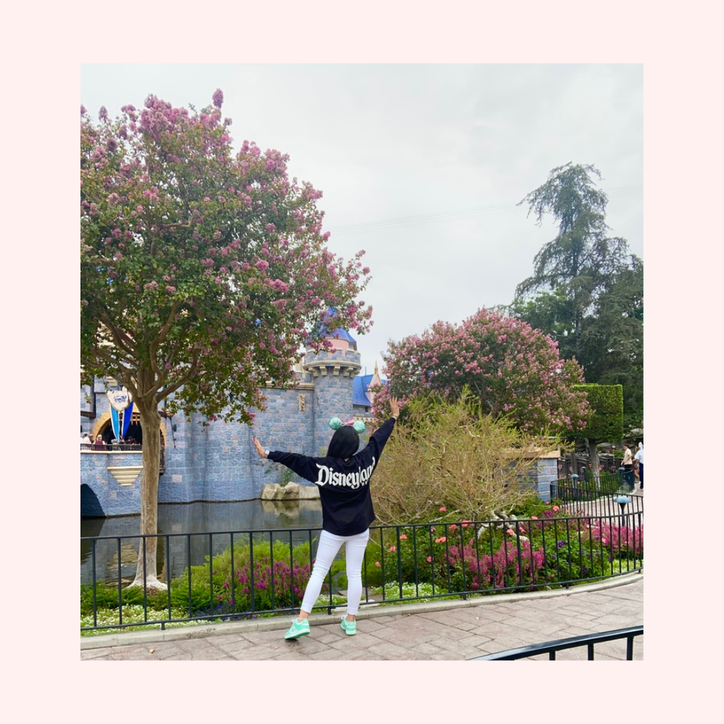 A young woman stretching her arms to show her spirit jersey and Ariel mickey ears