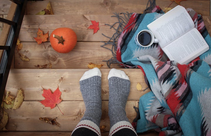 Socked feet with pumpkins, books, and leaves