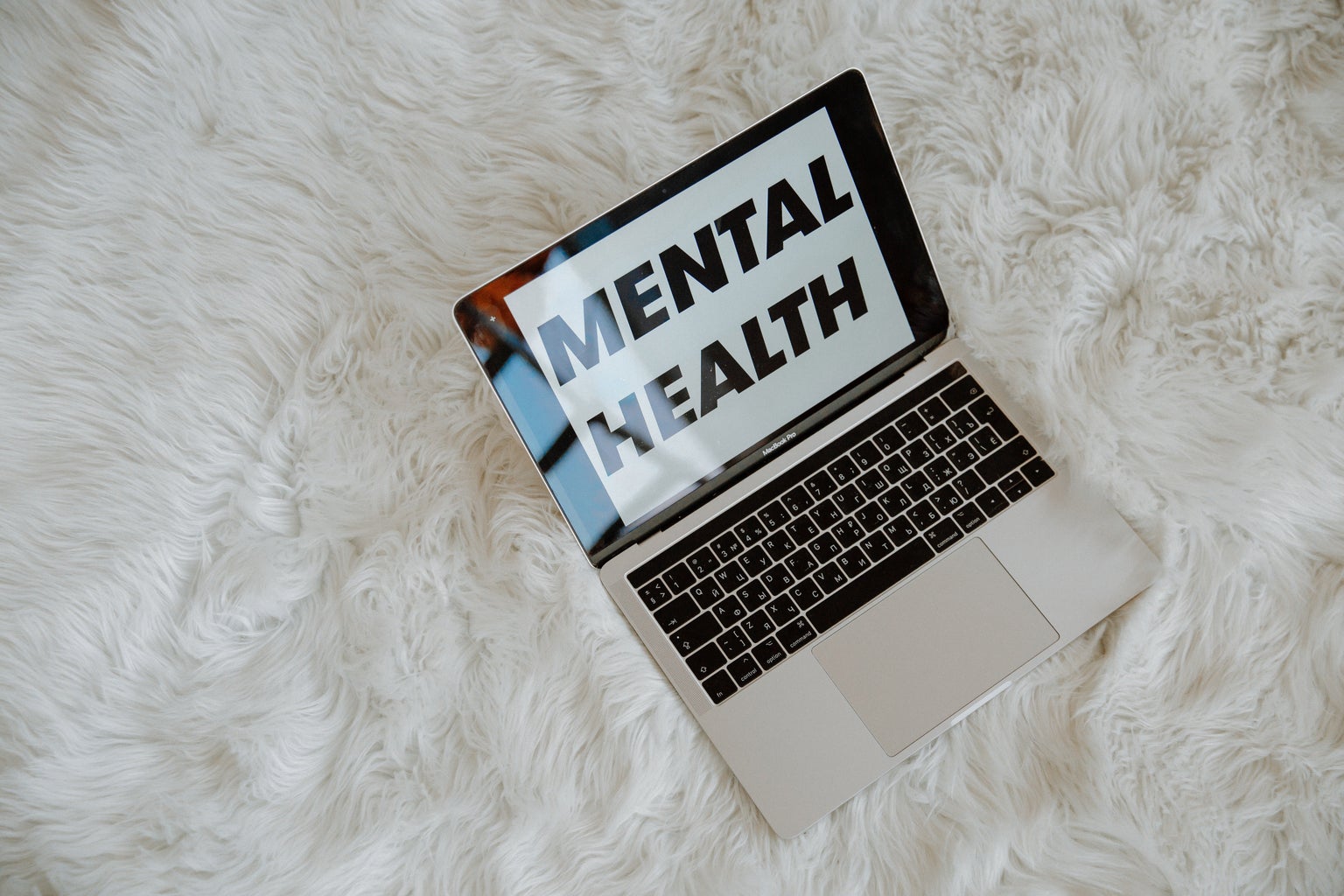 Laptop with text on the screen that reads "Mental Health" on a white carpet