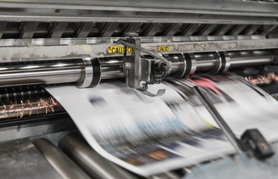 A newspaper in the process of being printed.