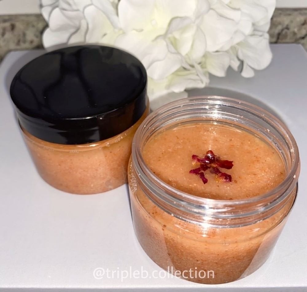 two containers of body scrub, one with a black lid and one that is open.