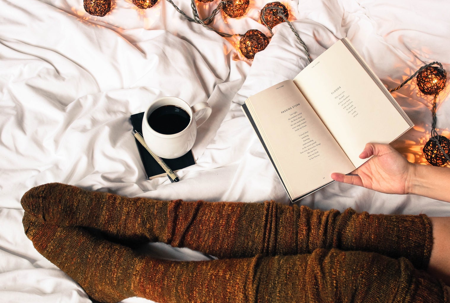 Mug of black coffee next to woman reading a book