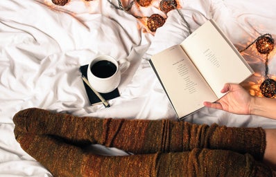 Mug of black coffee next to woman reading a book
