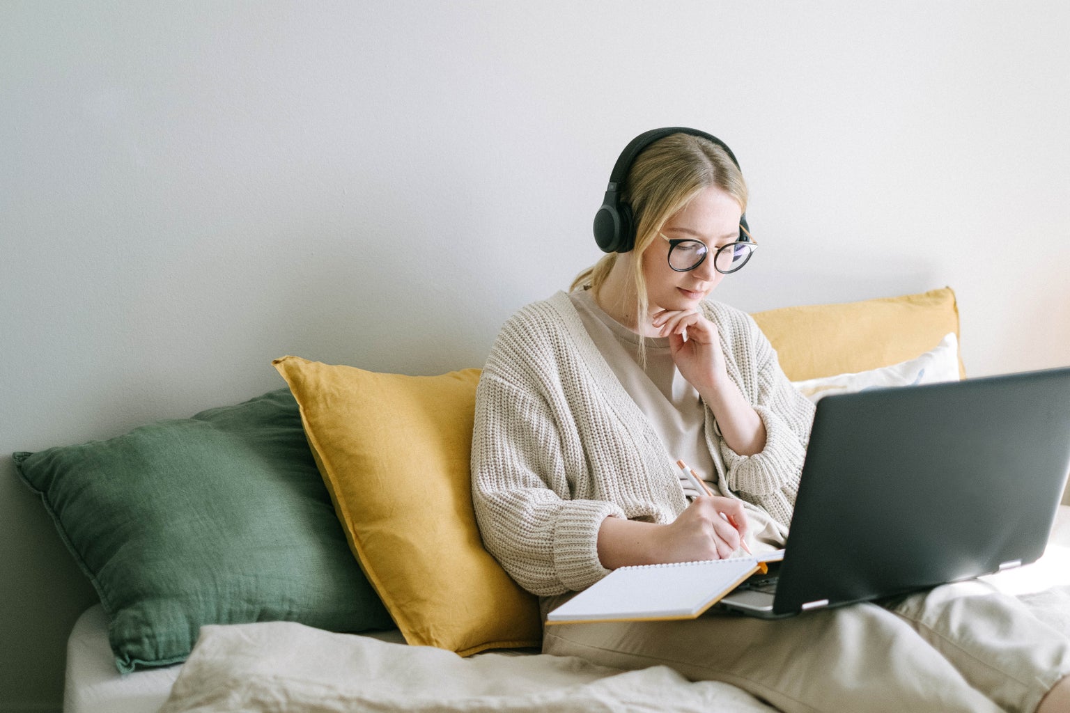 woman sits on bed with laptop