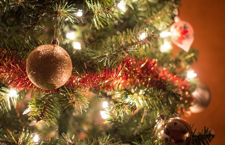 zoomed in image of a section of a christmas tree with a heavy emphasis on a sparkly, gold, circular ornament