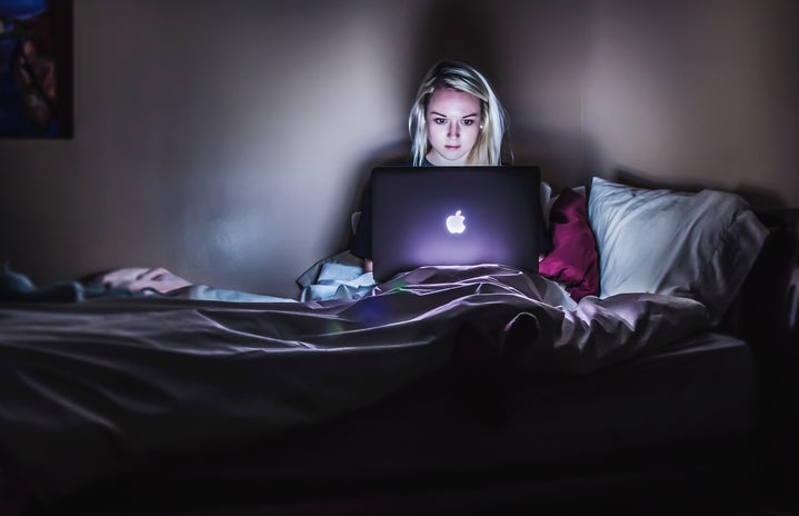 blonde girl in dark room on her laptop