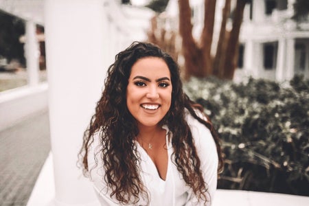 woman with curly brown hair and white dress