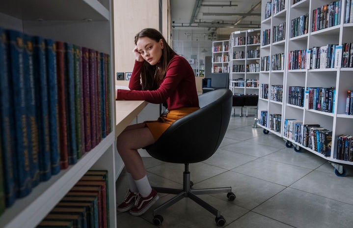 young person sad sitting alone in library