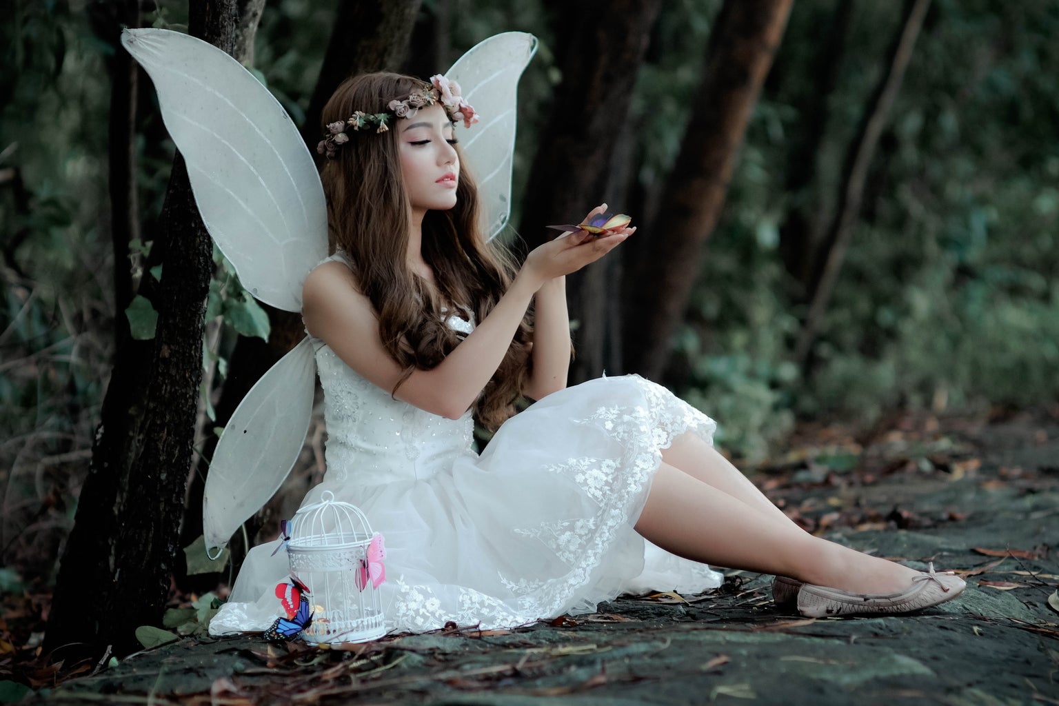 girl dressed like a fairy in a forest holding butterflies