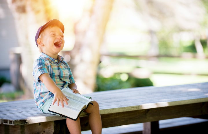 young boy sitting on bench while smiling