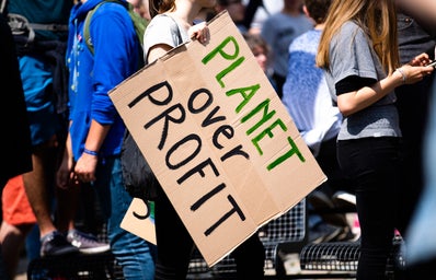 person holding a sign that says "planet over profit"