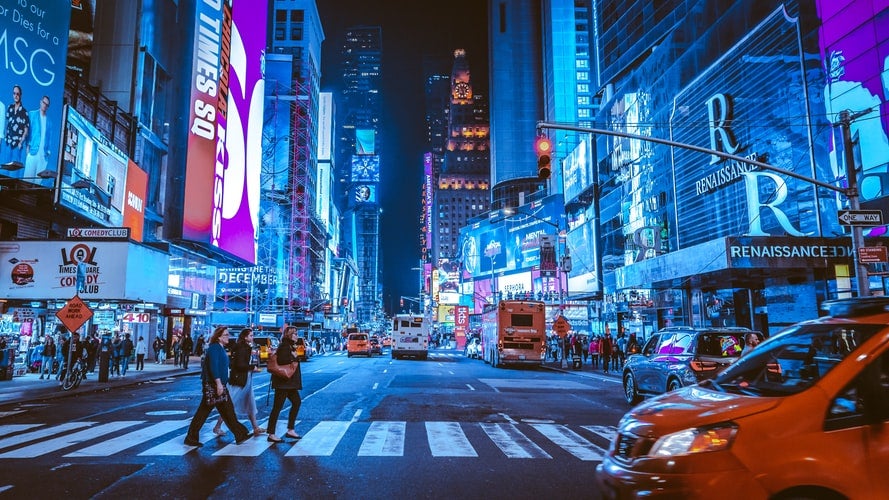people walking on crosswalk in NYC at nighttime