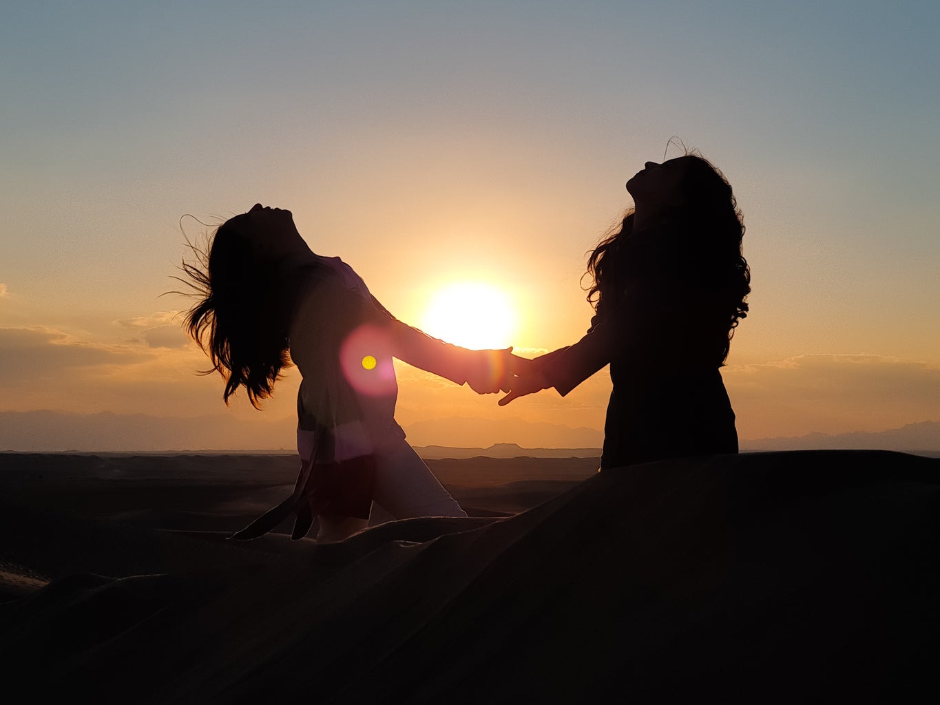 silhouette photo of two women holding hands