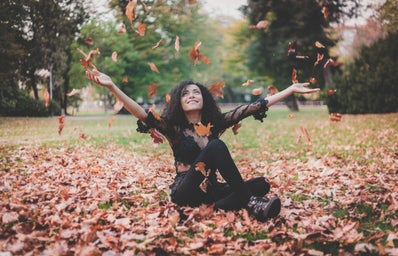 Woman sitting in leaves during fall time