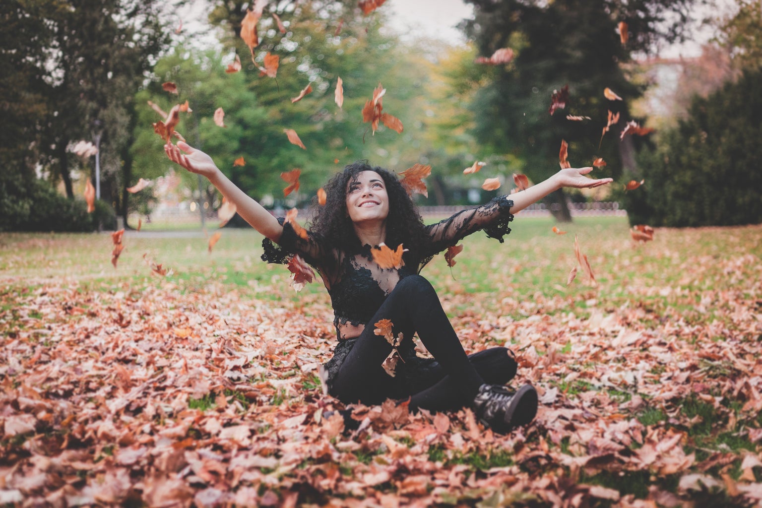 Woman sitting in leaves during fall time