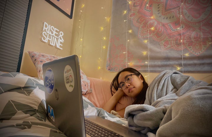 girl watching movie on laptop snuggled in blanket