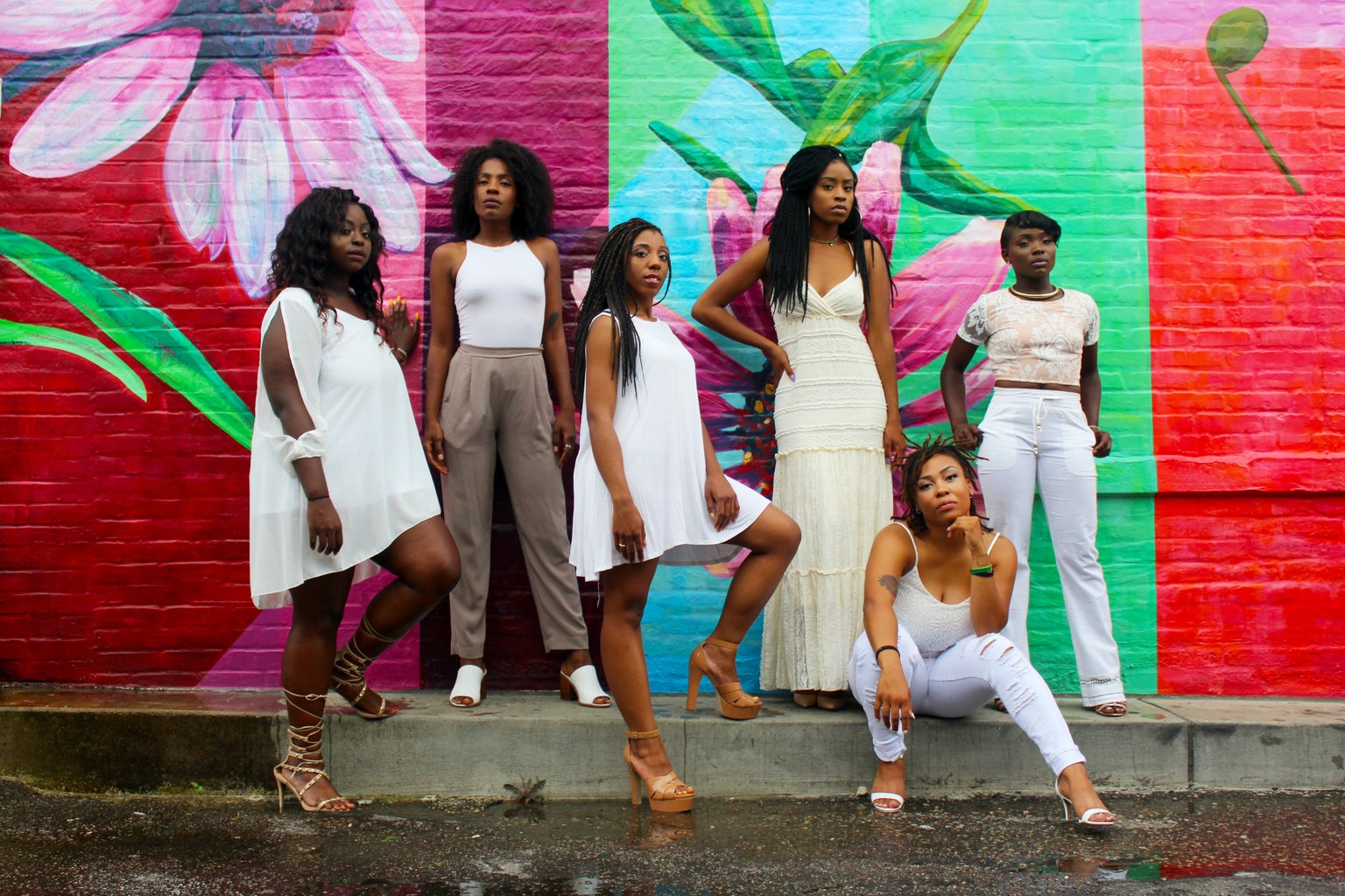 six Black women in white standing against a floral wall