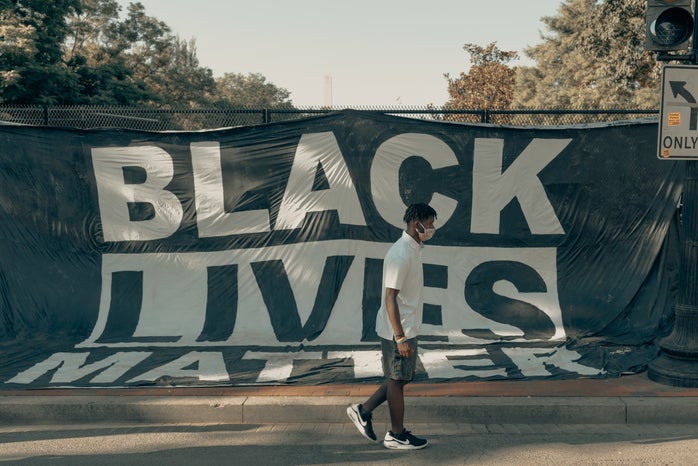 Black Lives Matter sign with man walking in front of it