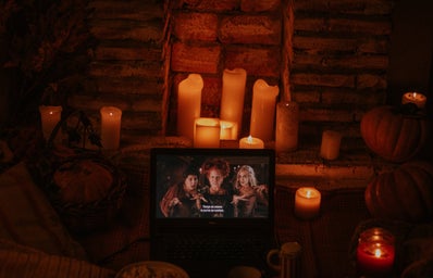 laptop playing "Hocus Pocus" in a room with candles and popcorn