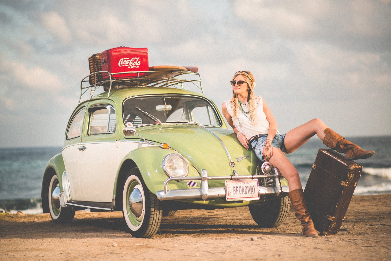 woman with suitcase on beach with vw beetle