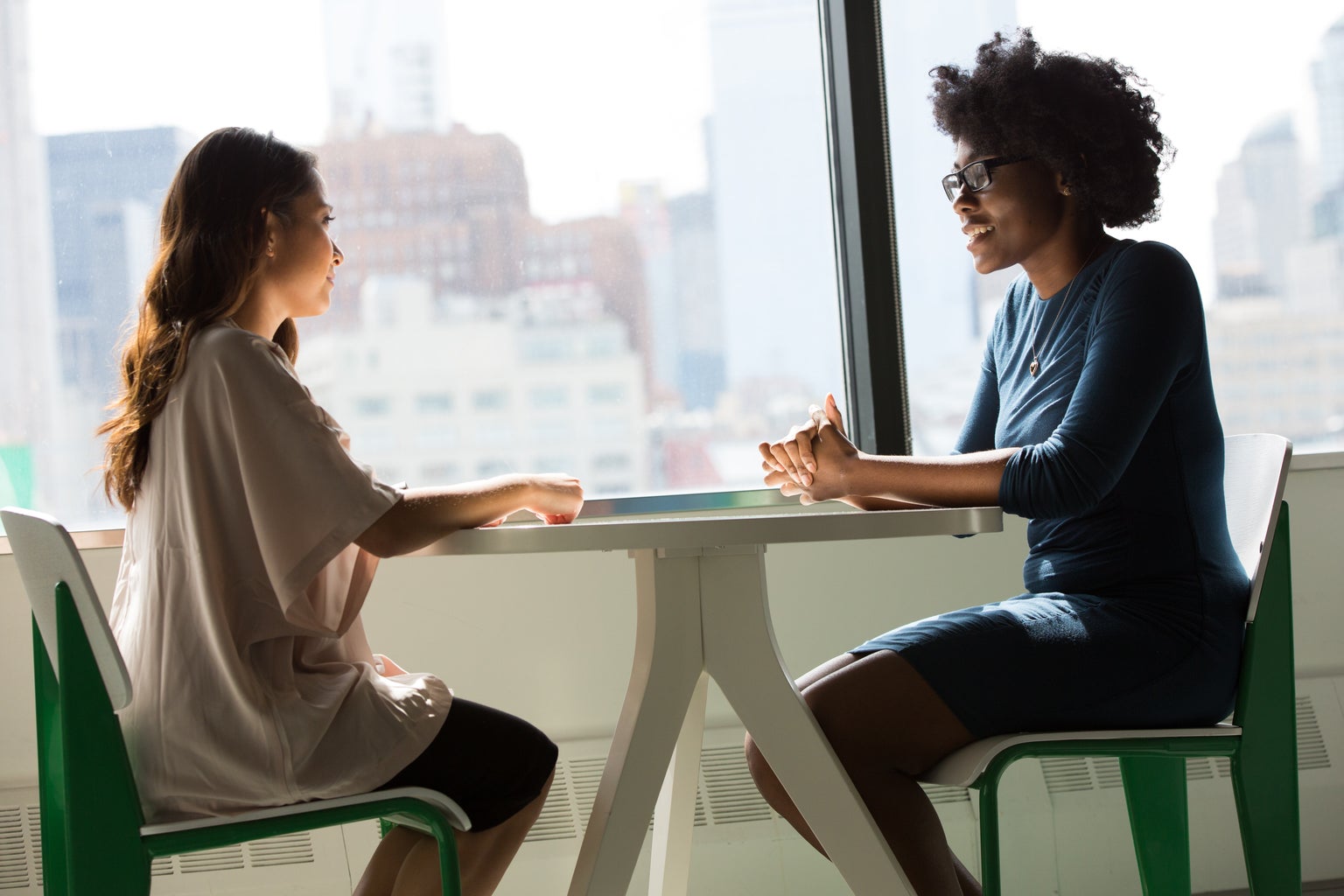 Two women sit at a table and talk