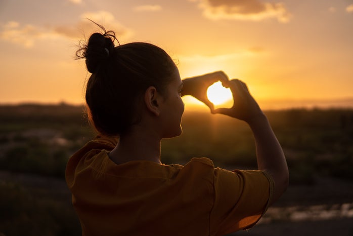 Girl holding heart in sunset