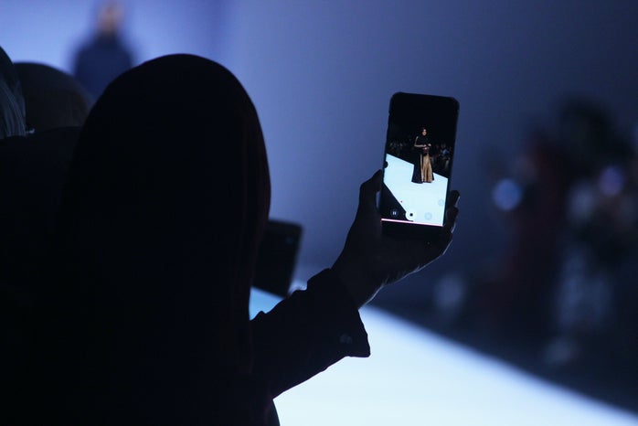 Person taking a picture of a woman during a fashion show