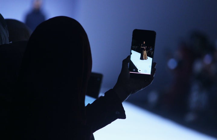 Person taking a picture of a woman during a fashion show