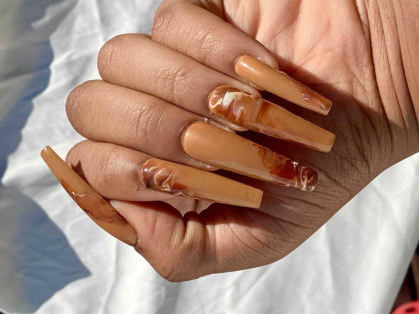 close up of hands with tan and gold acrylic nails