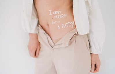 A model\'s exposed stomach reads \"I am more than a body.\"