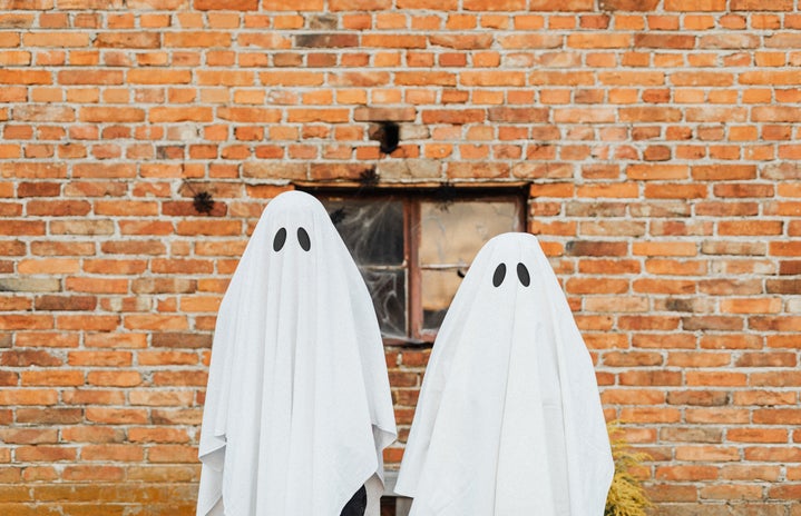 Two Ghosts Standing in Front of a Brick Wall