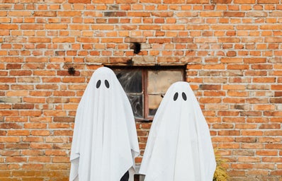 Two Ghosts Standing in Front of a Brick Wall