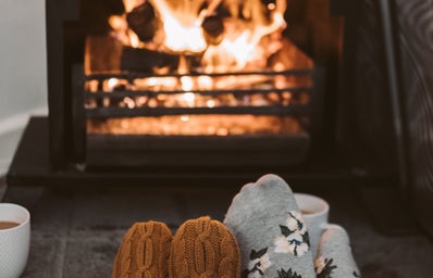 Person Wearing Gray and White Socks Near Brown Fireplace