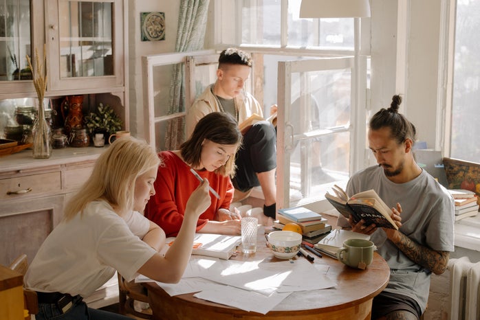 group of people studying and reading at a kitchen table
