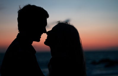 silhouette of man and woman kissing at sunset