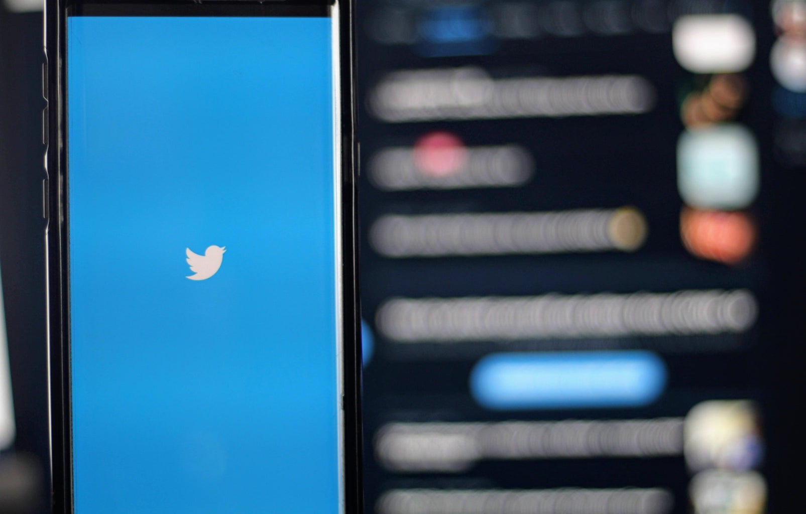 Twitter logo in front of a blurred screen