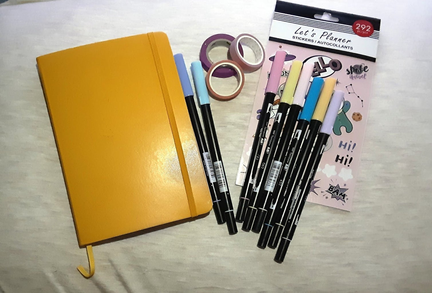 Supplies needed for bullet journal planning: bullet journal, dual brush pens, and washi tape.