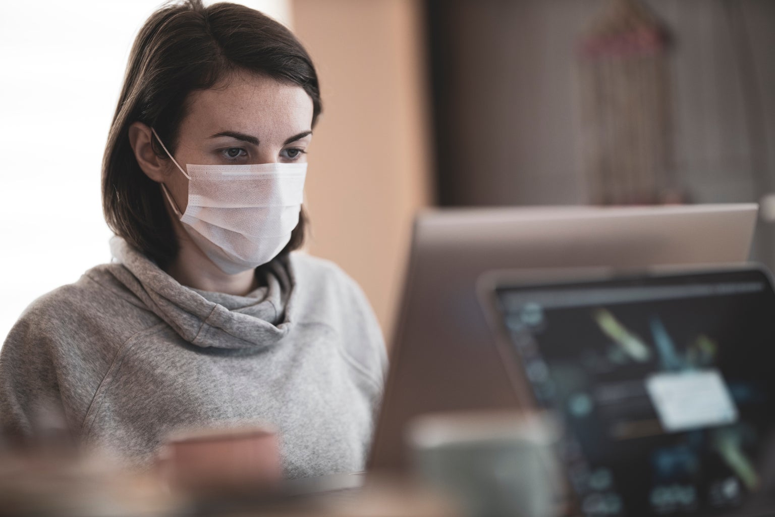 woman looking at a computer while wearing a mask