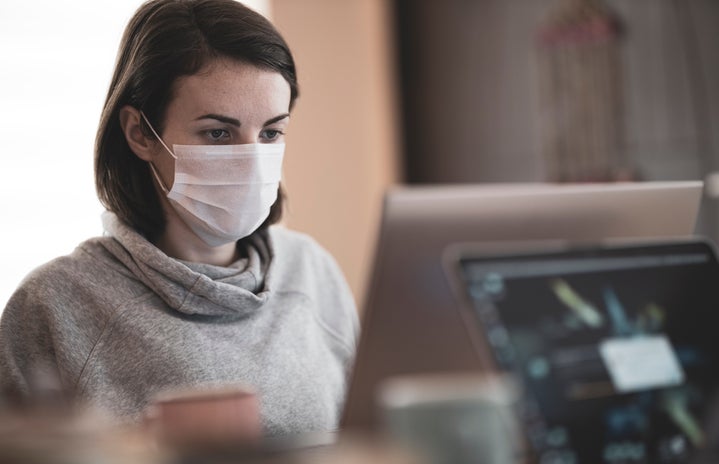 woman looking at a computer while wearing a mask